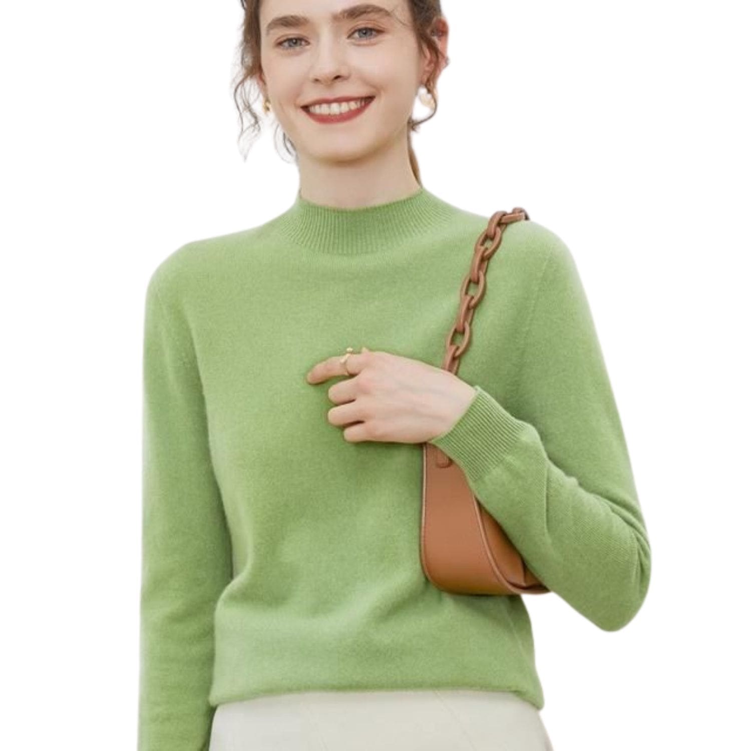 Woman wearing a light green mock-neck cashmere knit sweater with long sleeves, holding a small brown shoulder bag.