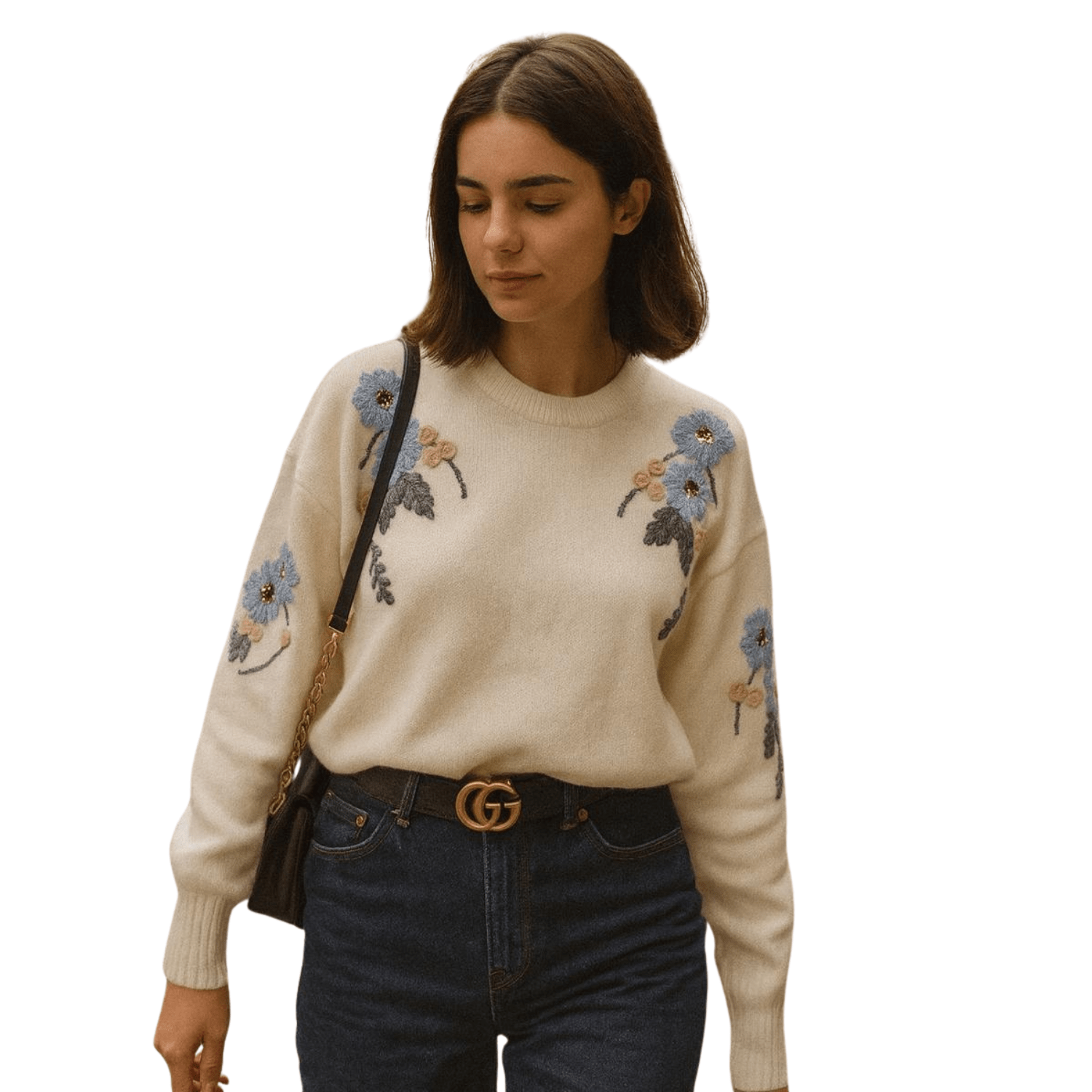 Woman wearing a cream knit sweater with delicate embroidered floral details, paired with blue jeans
