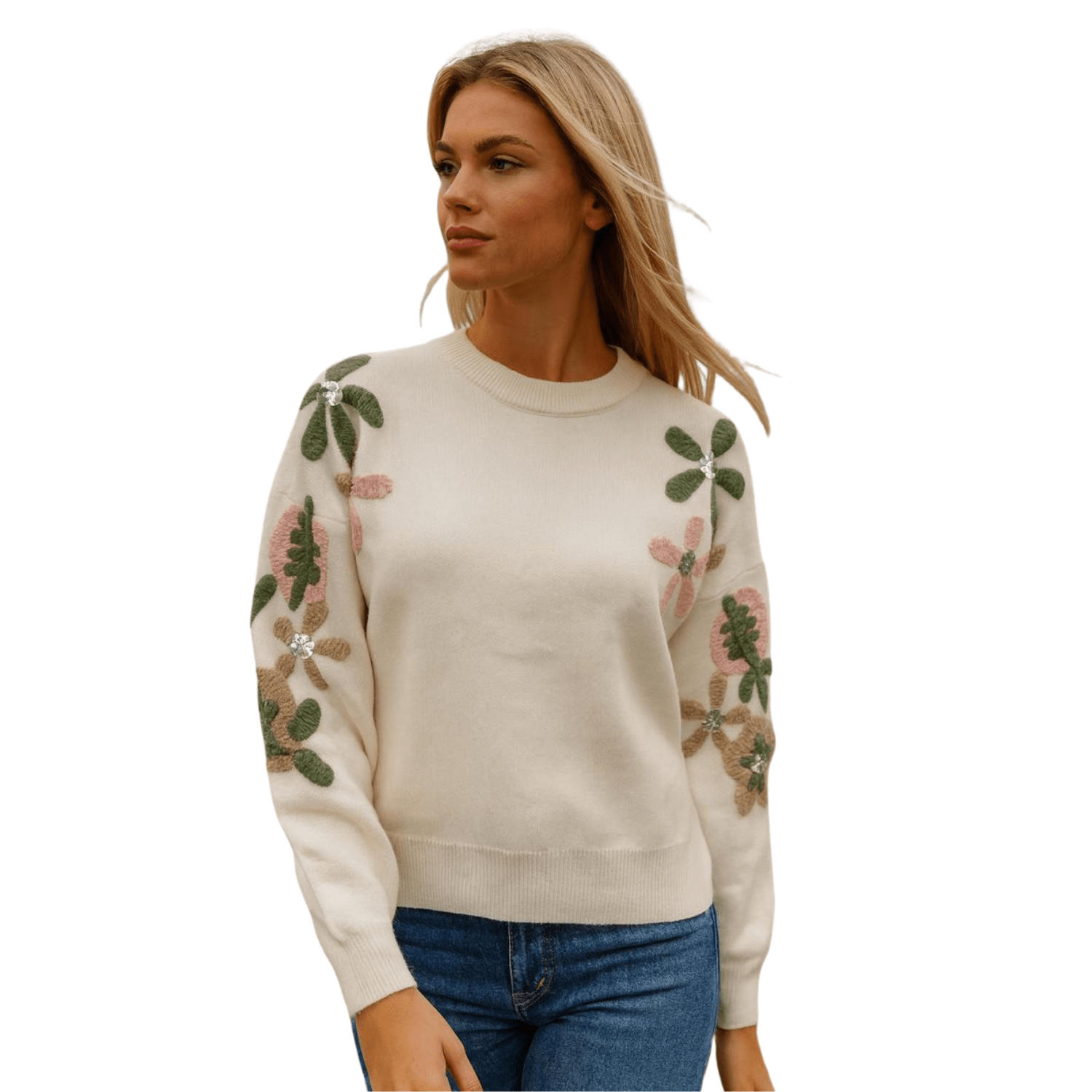 Woman wearing a cream knit sweater with embroidered floral sleeves, styled with blue jeans