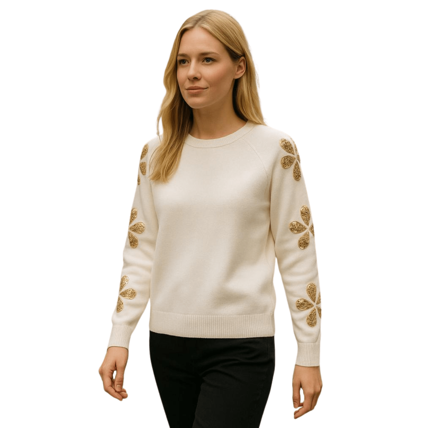 Woman wearing a cream knit sweater with gold embroidered floral details on the sleeves, paired with black pants