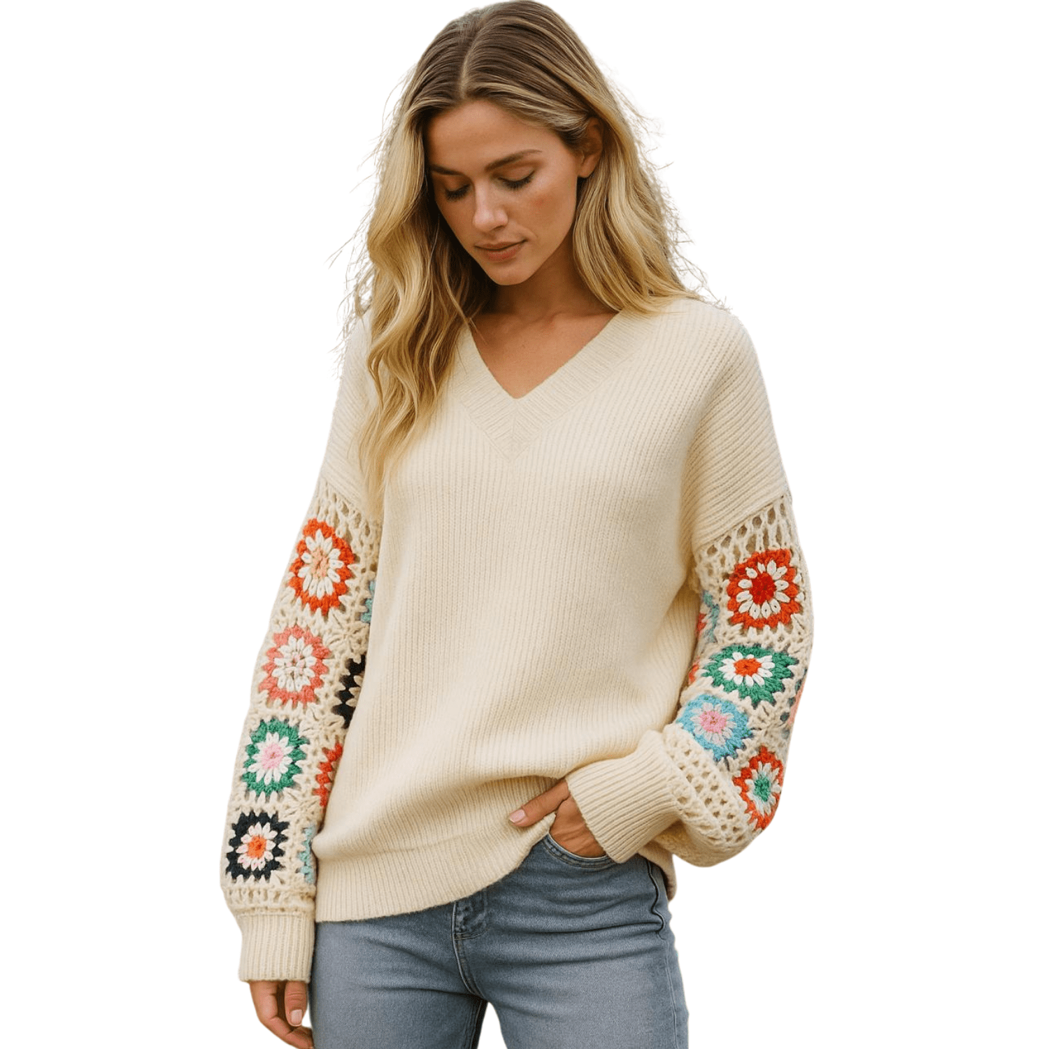 Woman wearing a cream V-neck knit sweater with colorful crochet detail sleeves, styled with blue jeans