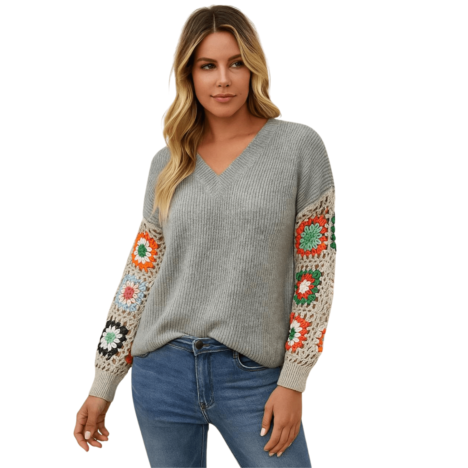 Woman wearing a gray V-neck knit sweater with colorful crochet detail sleeves, paired with blue jeans