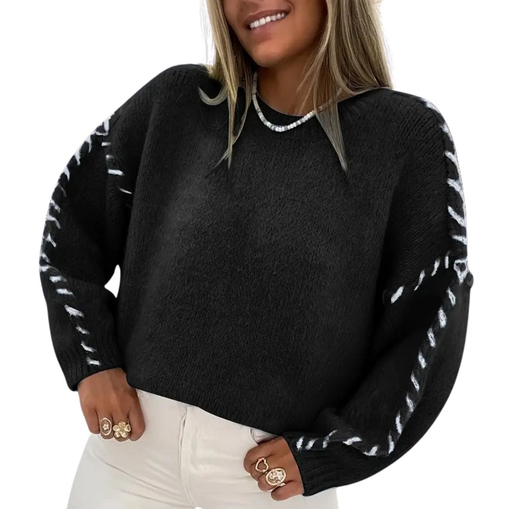 “Woman wearing a black cozy knit sweater with white braided sleeve detail and long sleeves.”